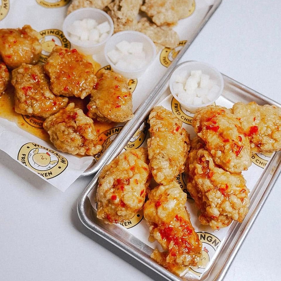 Two trays of WingNow fried chicken with sweet chili sauce and small cups of pickled radish.